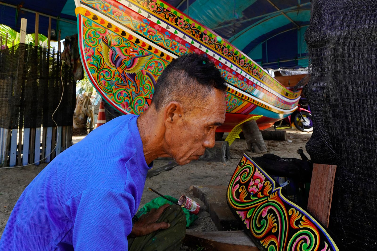 Craftsman painting traditional patterns on a Kolae fishing boat in Narathiwat
